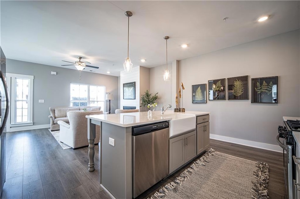 Kitchen with appliances with stainless steel finishes, gray cabinets, dark wood finished floors, light countertops, and open floor plan