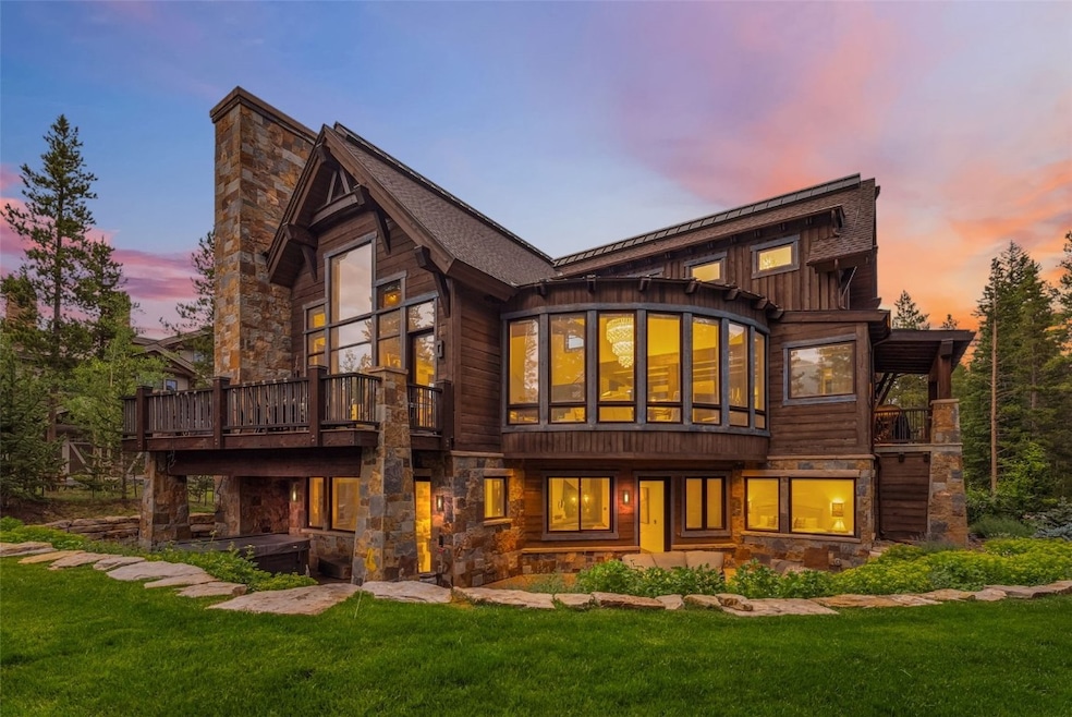 Back of property with a lawn, stone siding, a deck