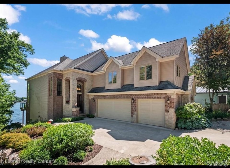 View of front of house with concrete driveway, an attached garage, brick siding, and a chimney