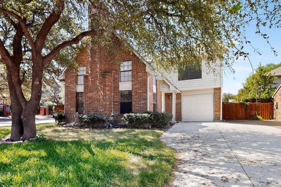 Traditional-style house featuring driveway, brick siding, and a garage
