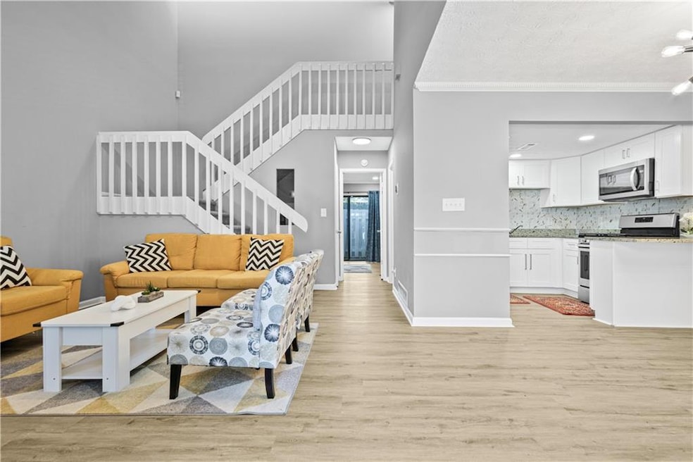 Living area with light wood finished floors, stairway, a textured ceiling, and a high ceiling