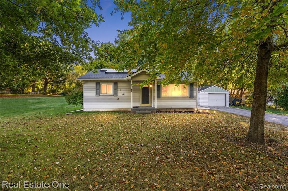 Bungalow-style home featuring solar panels, a front yard, asphalt driveway, and a detached garage
