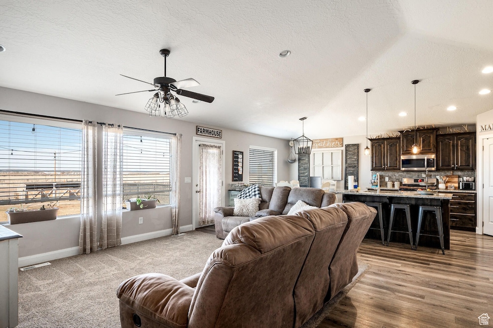 Living room featuring vaulted ceiling, recessed lighting, a textured ceiling, ceiling fan, and a chandelier