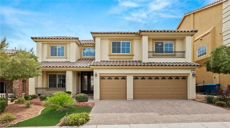 Mediterranean / spanish home featuring decorative driveway, stucco siding, a balcony, a garage, and a tiled roof