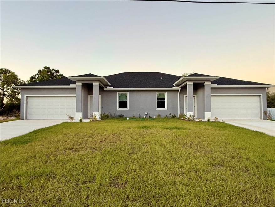 View of front facade with a lawn, stucco siding, driveway, and an attached garage