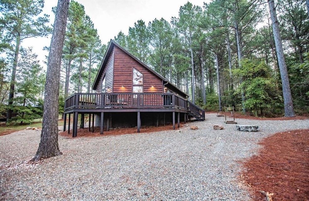 View of front of house featuring faux log siding and a wooden deck