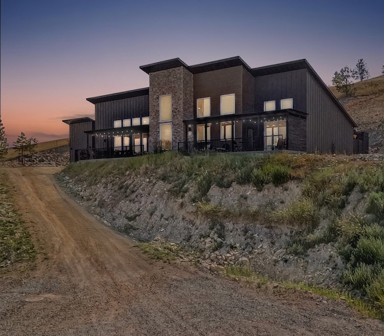 Back of property at dusk featuring stone siding