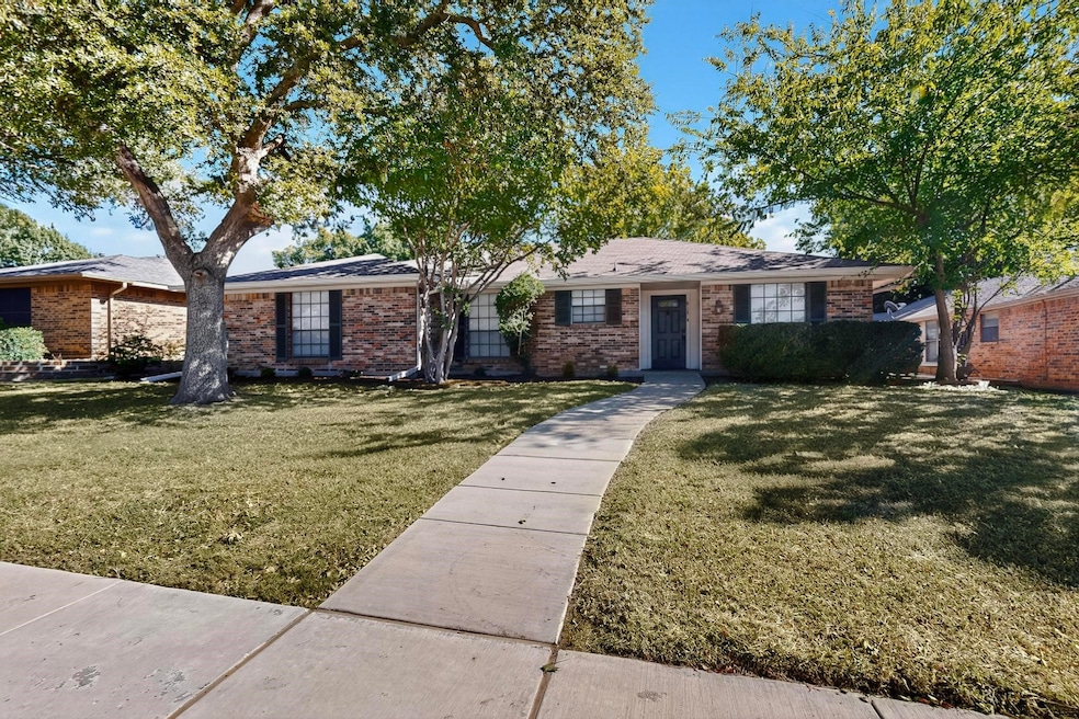 Ranch-style home with a front yard, brick siding, and a shingled roof