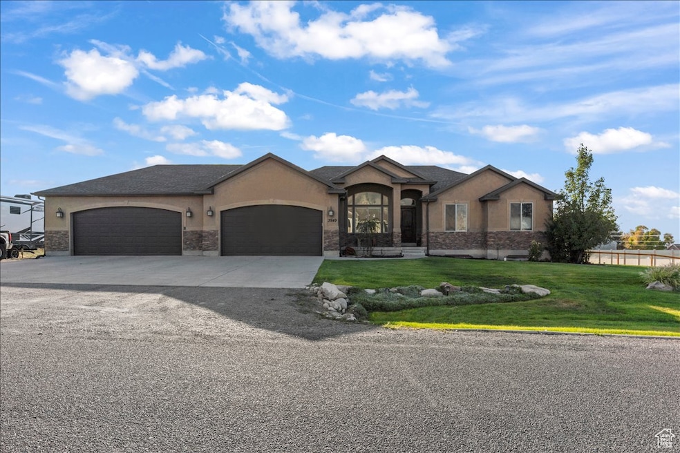 View of front facade featuring stucco siding, a front lawn, an attached garage, and driveway