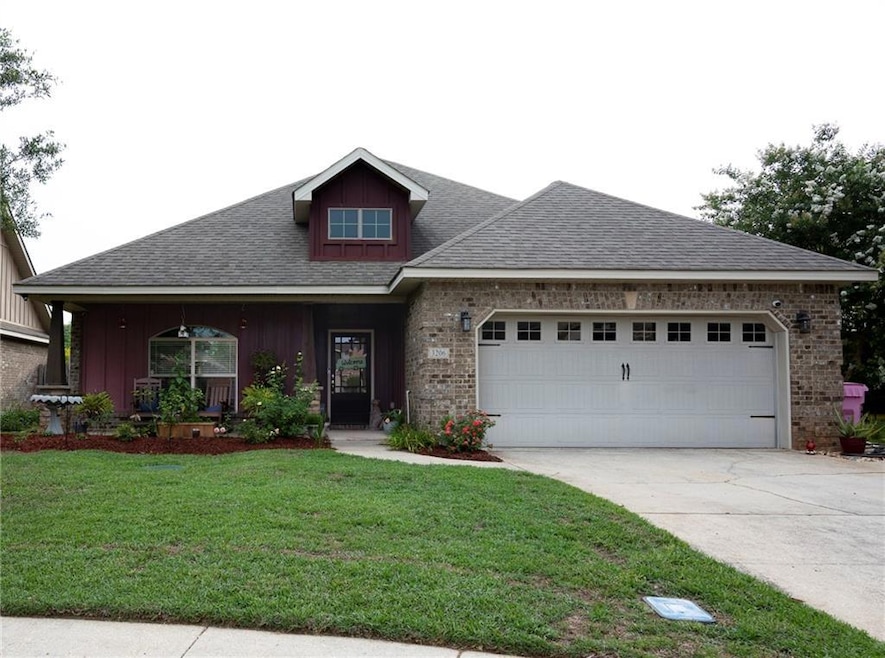 Craftsman-style house featuring concrete driveway, an attached garage, a front yard, board and batten siding, and brick siding