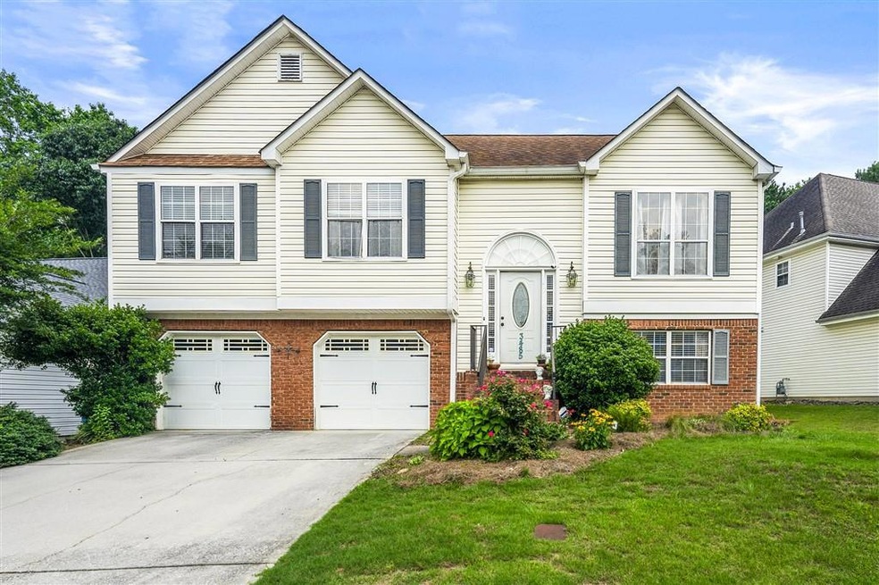 Split foyer home featuring brick siding, a front yard, driveway, and a garage