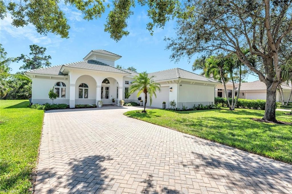 Mediterranean / spanish-style home featuring a front lawn, a tile roof, decorative driveway, and an attached garage