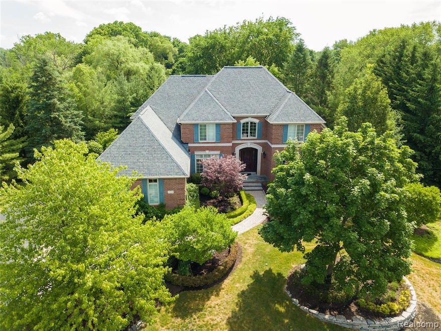 View of front facade featuring brick siding, a shingled roof, a view of trees, and a front yard