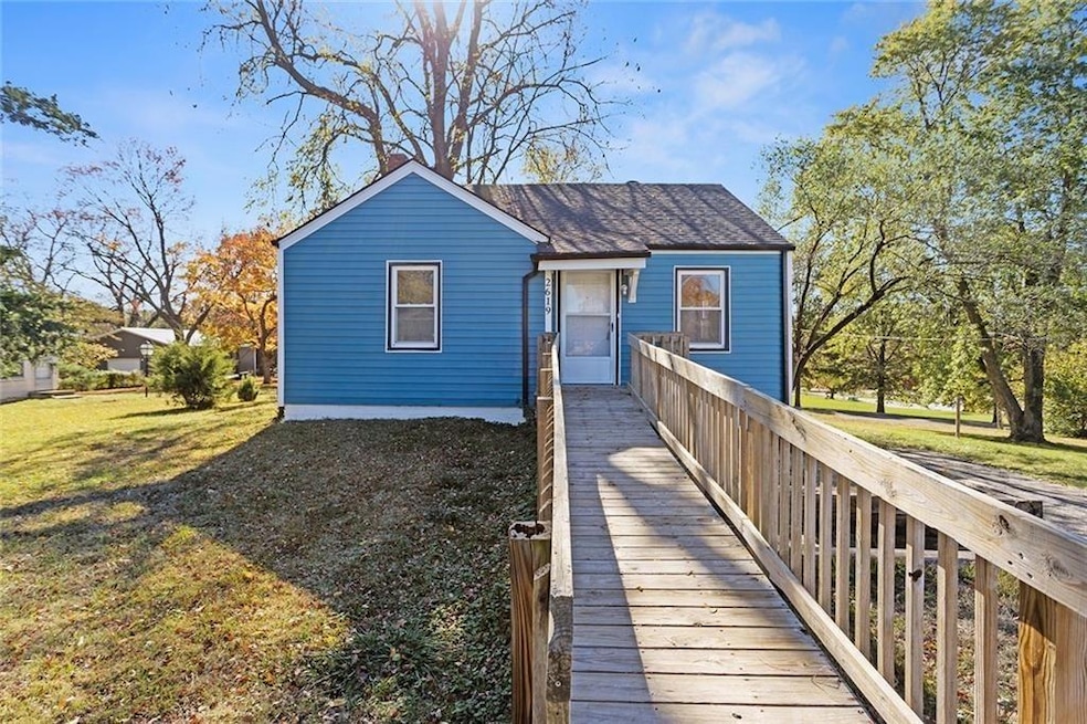 Back of house featuring a lawn and roof with shingles
