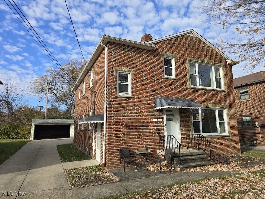 Traditional home with brick siding, a chimney, and a detached garage