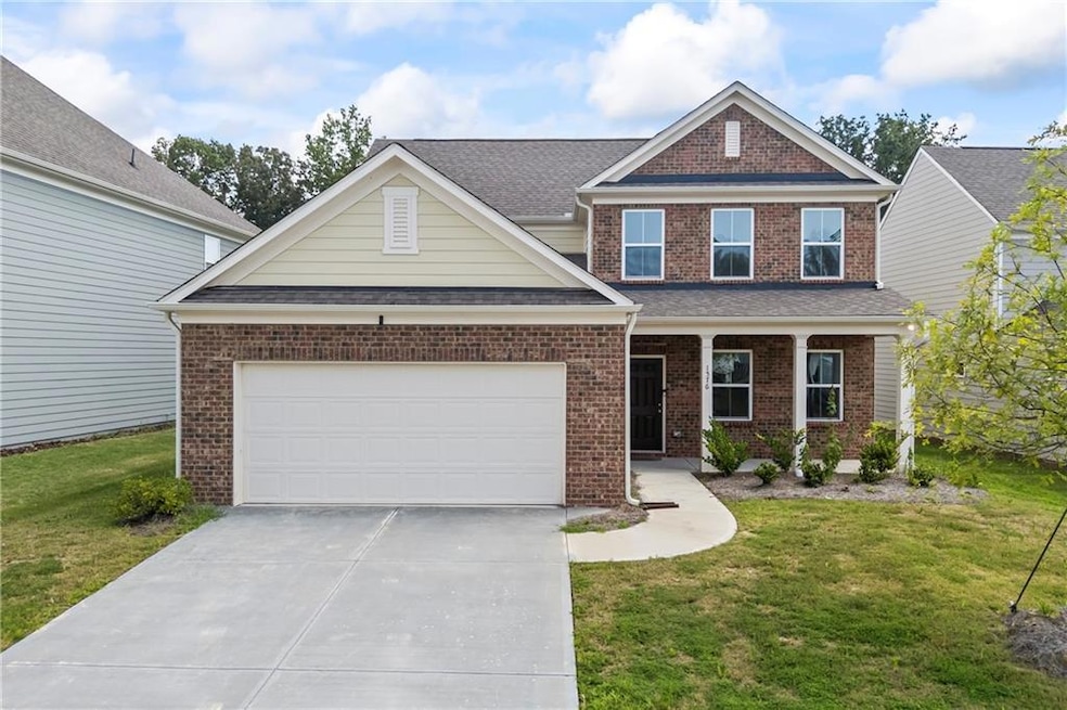 View of front of house with driveway, brick siding, an attached garage, and a front lawn