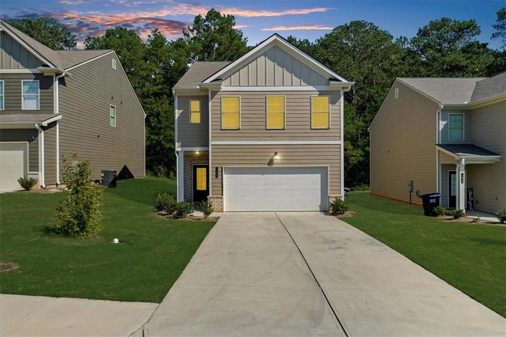 View of front facade featuring board and batten siding, an attached garage, a yard, and concrete driveway
