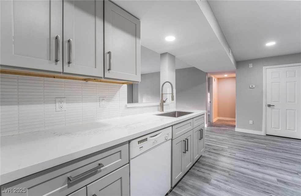 Kitchen featuring sink, light wood-type flooring, dishwasher, gray cabinets, and tasteful backsplash