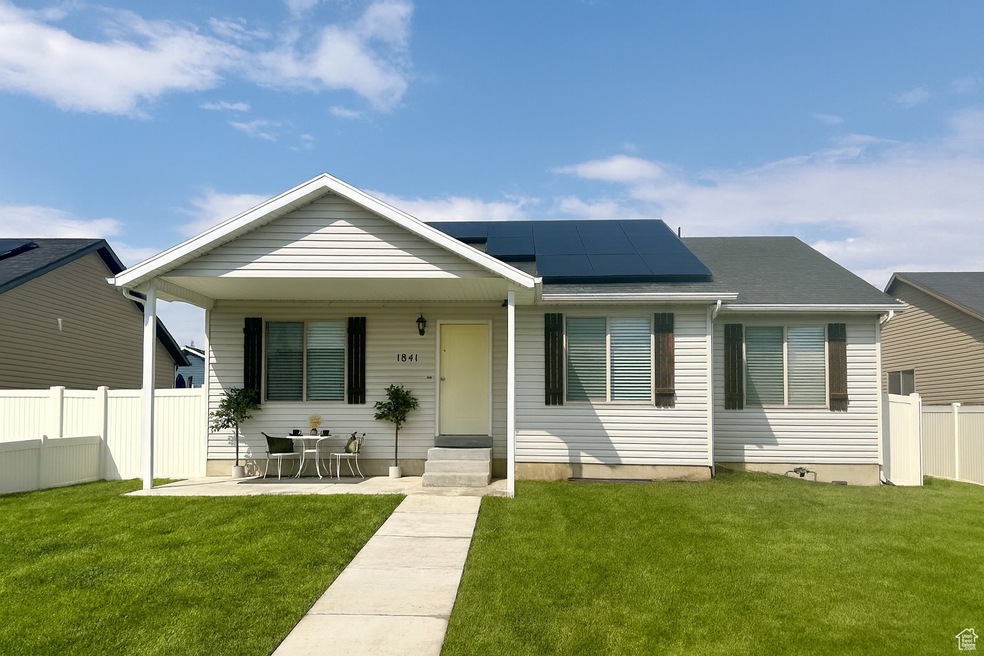 View of front facade with roof mounted solar panels and a porch