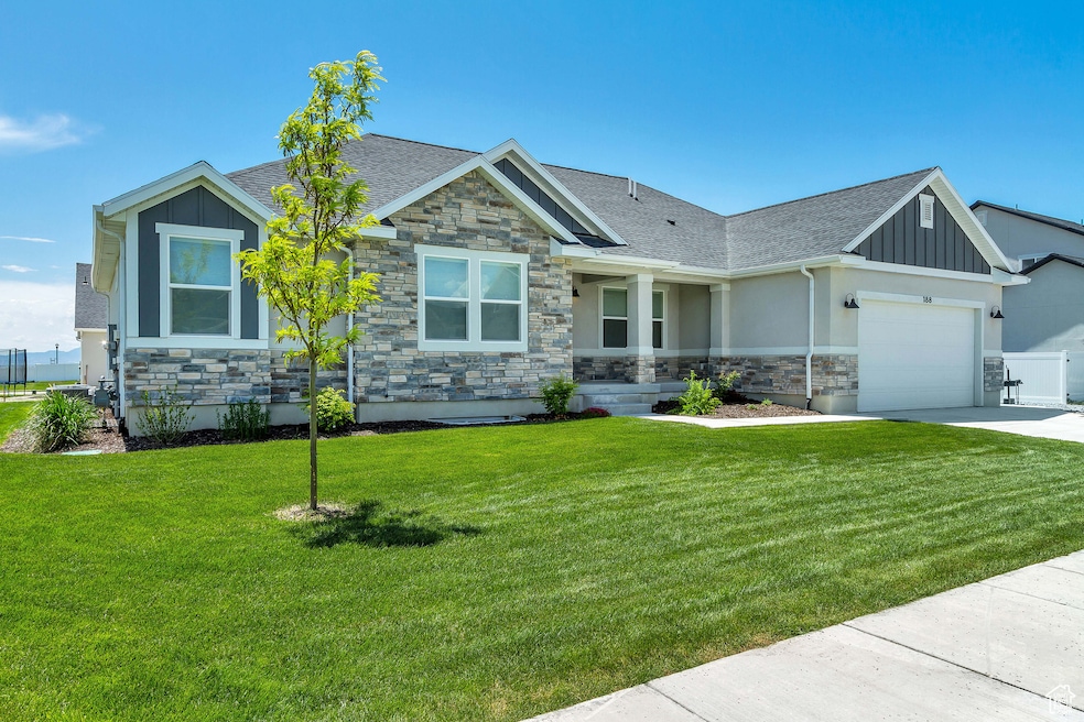 Craftsman inspired home featuring stone siding, board and batten siding, a front lawn, roof with shingles, and a garage