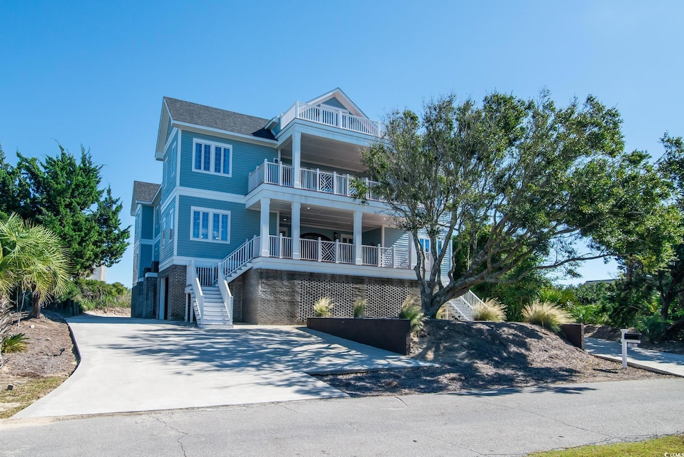 Coastal home with stairway, concrete driveway, a balcony, and a shingled roof