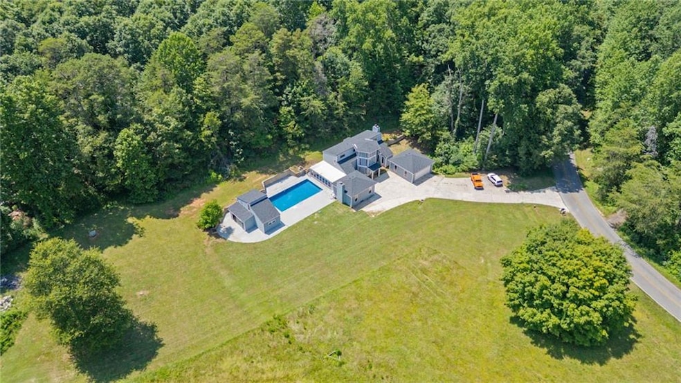 Aerial view of property and surrounding area featuring a pool area and a heavily wooded area