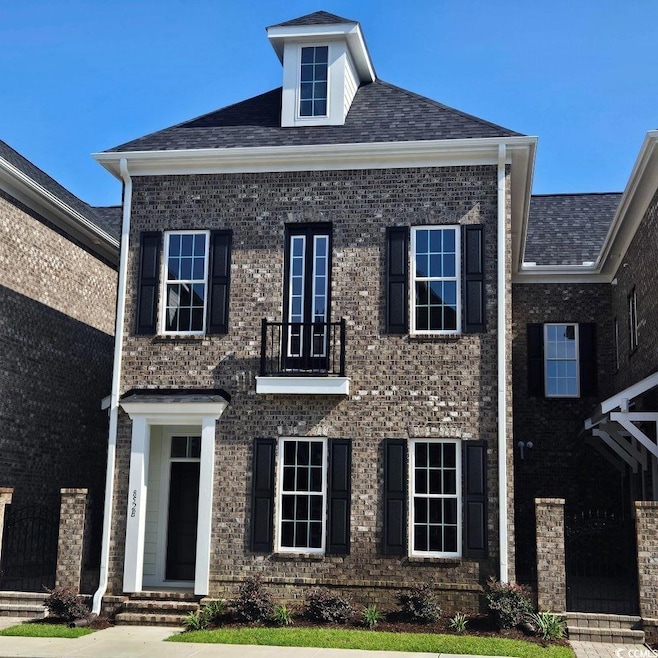 View of front of house featuring brick siding and a balcony