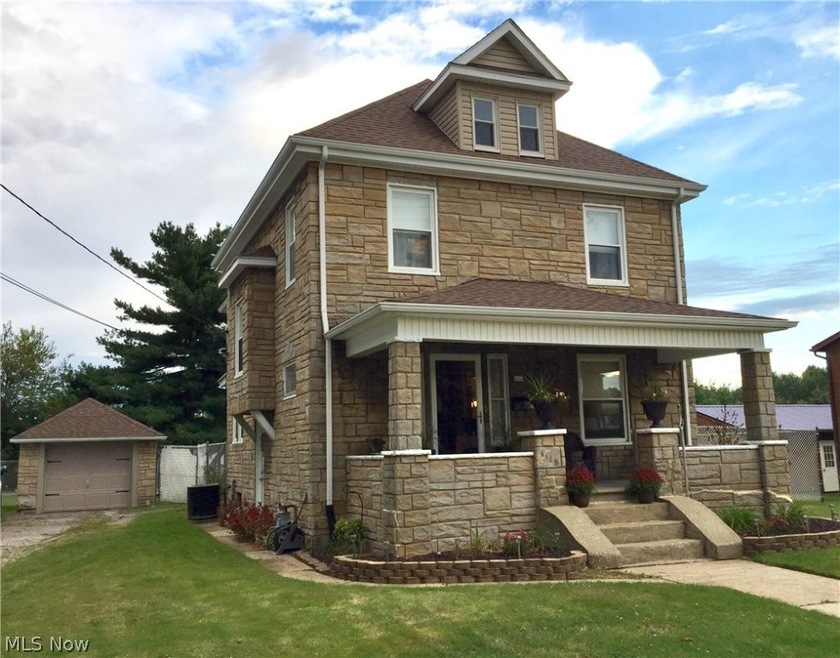 Front view of beautiful Stone 2 story home with large front porch, fenced in yard and many updates