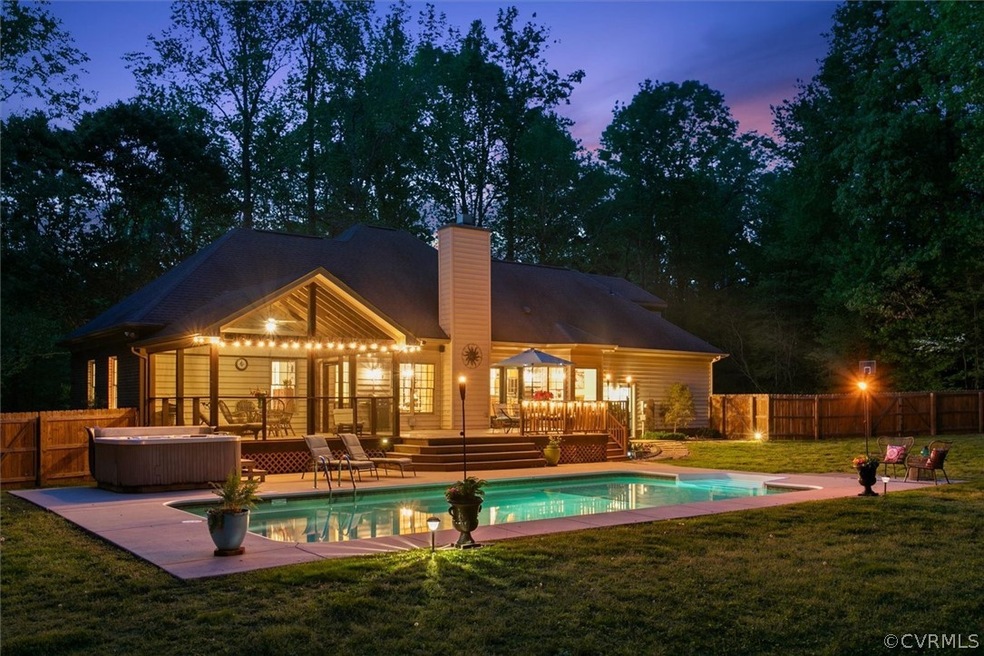 Back house at dusk with a lawn and a swimming pool with hot tub