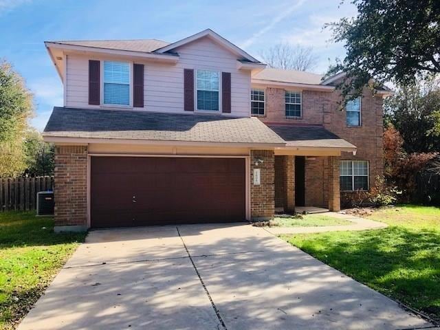Traditional home with brick siding, driveway, a front yard, and an attached garage