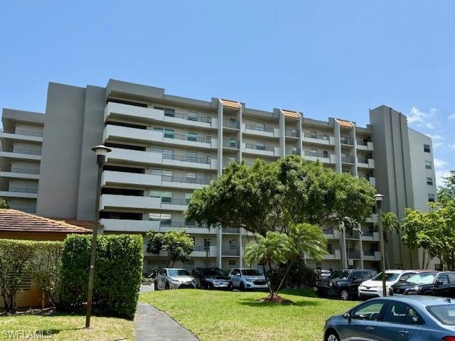 View of apartment building / complex featuring uncovered parking