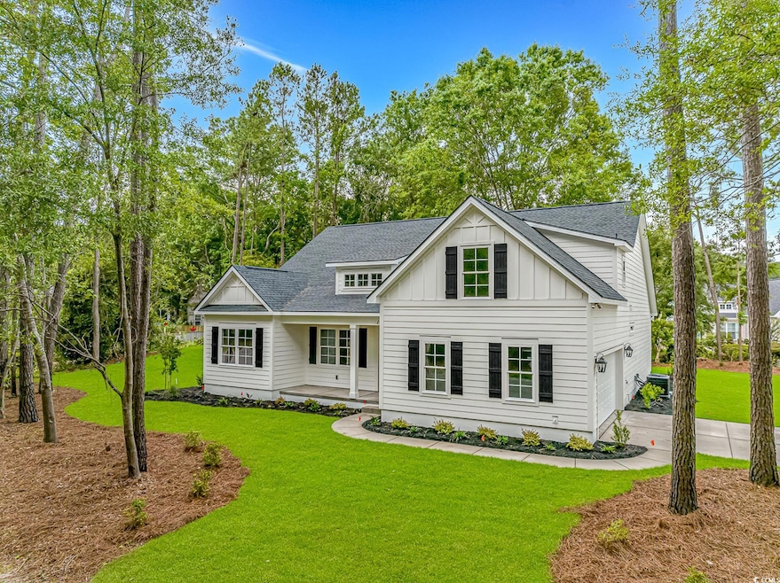 Modern inspired farmhouse featuring board and batten siding, roof with shingles, a front lawn, and driveway