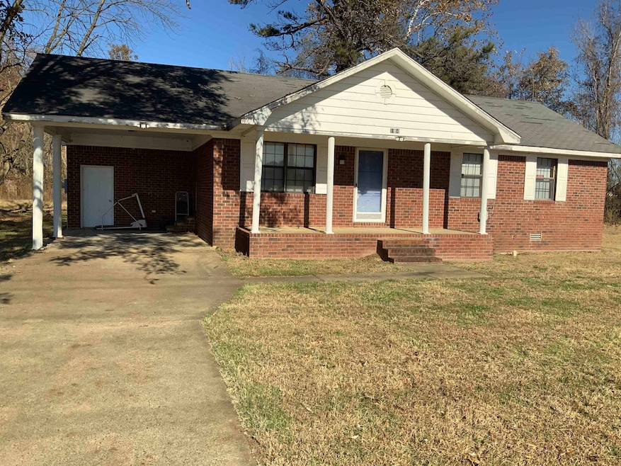 Ranch-style home with a porch, a carport, driveway, and a front lawn