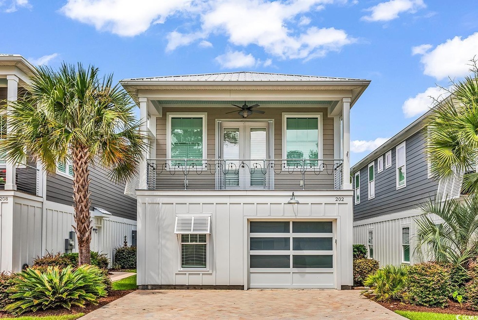 View of front facade with ceiling fan, board and batten siding, a balcony, decorative driveway, and a garage