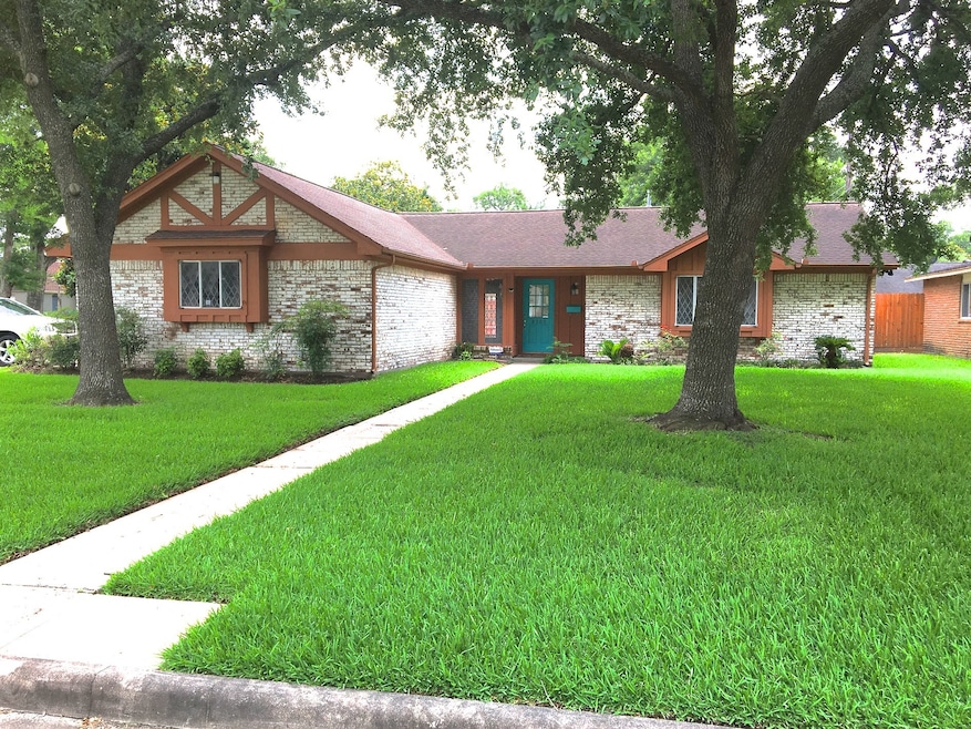 View of the front door with the great yard and live oak trees for shade. The garage comes off the side of this corner lot property.