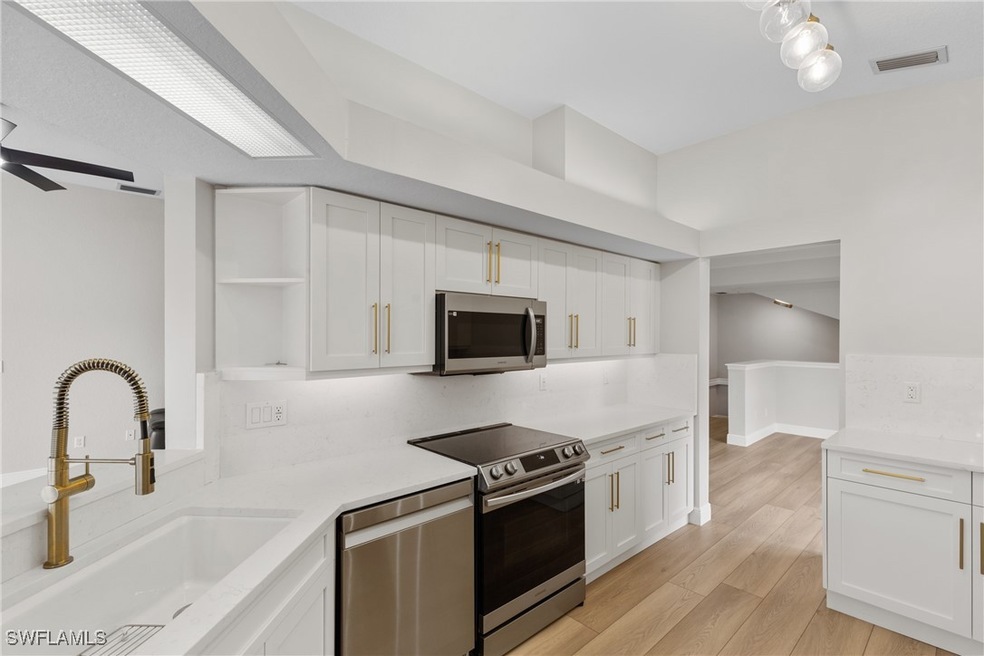 Kitchen with white cabinetry, sink, appliances wit