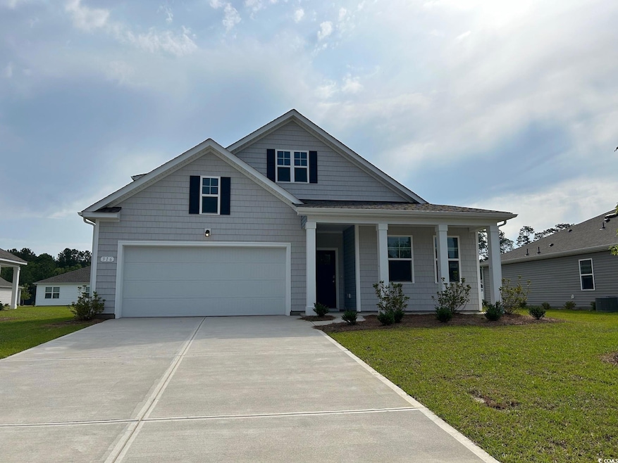 View of front of property featuring concrete driveway, a front yard, a porch, and a garage