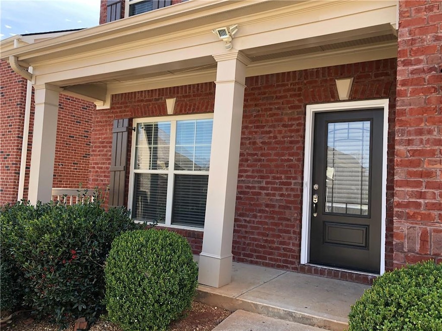View of exterior entry featuring covered porch and brick siding