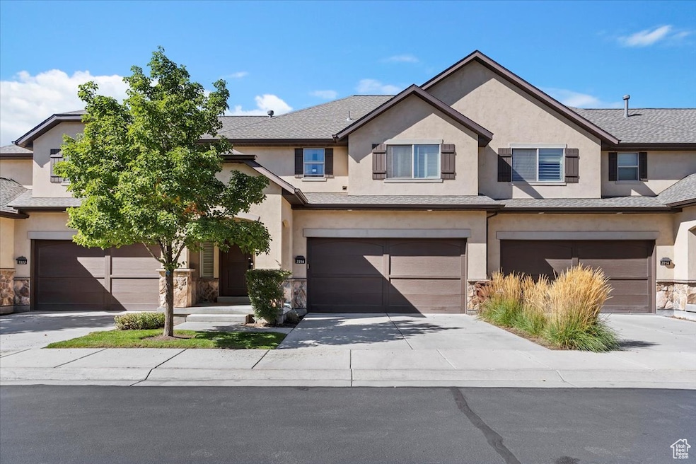 Traditional-style house with stucco siding, driveway, stone siding, and a garage