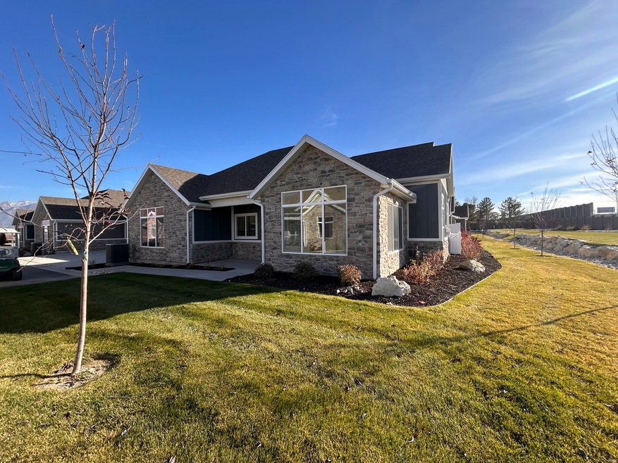 View of front of house with a front yard, stone siding, and roof with shingles