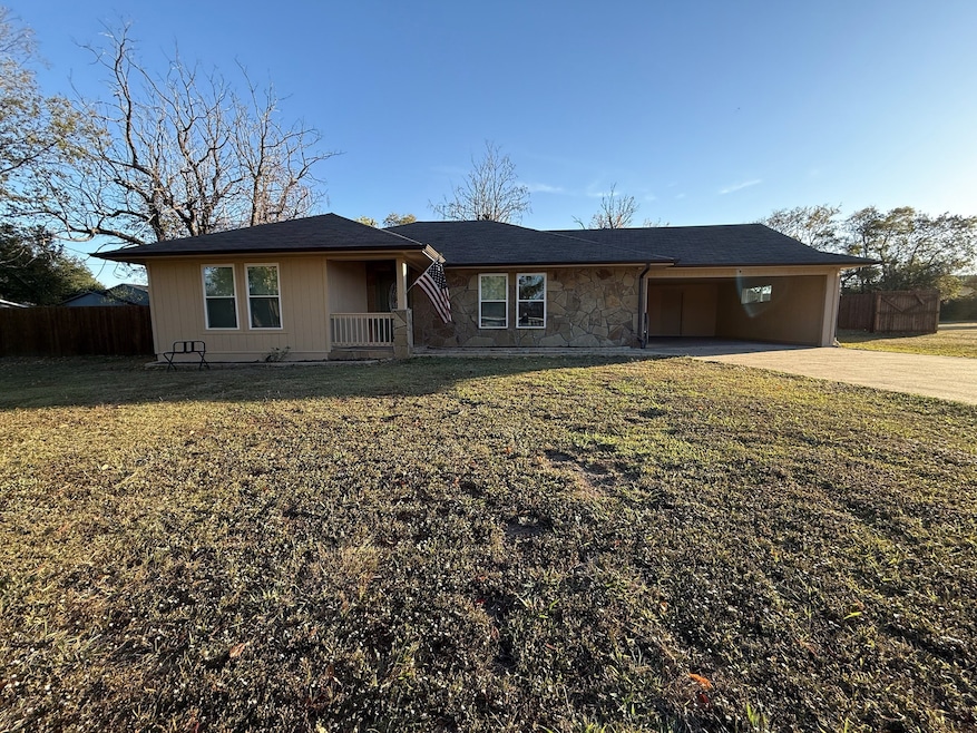 Ranch-style house with concrete driveway, stone siding, and roof with shingles