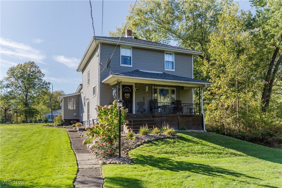 Traditional style home featuring a front lawn, covered porch, and a chimney