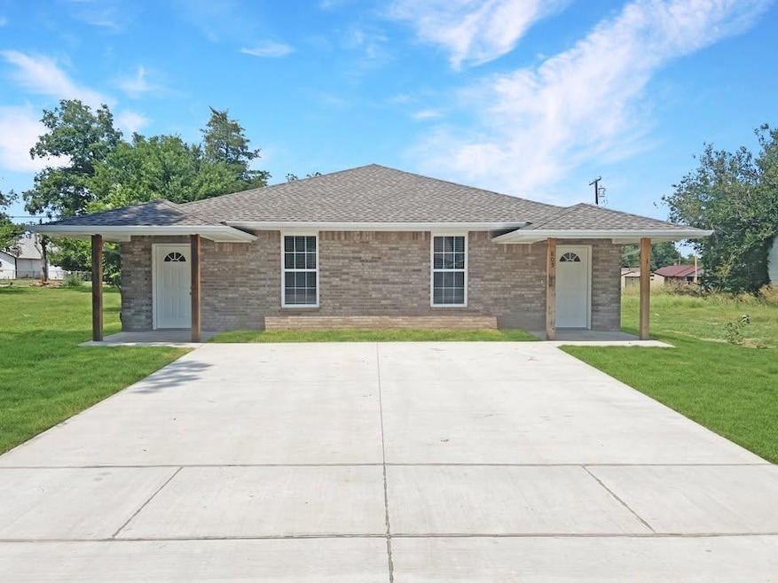 Front view of a duplex with a brick exterior, covered entryways, and a wide concrete driveway offering ample parking space.Note: Photos are of a similar home by the builder.