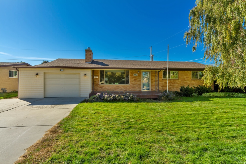 Single story home with a front yard, a chimney, driveway, and an attached garage