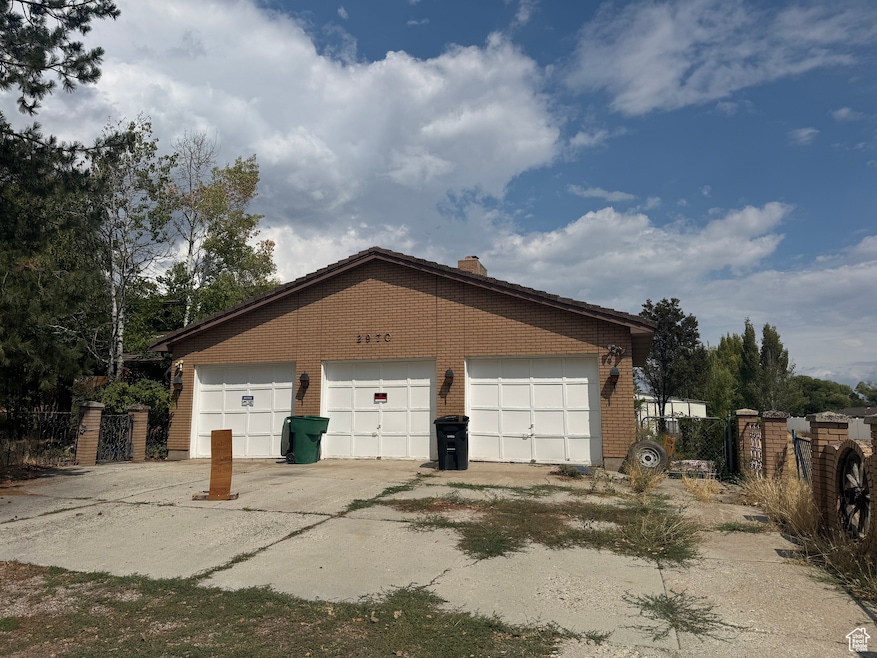 View of property exterior with a garage, brick siding, an outbuilding, and a chimney