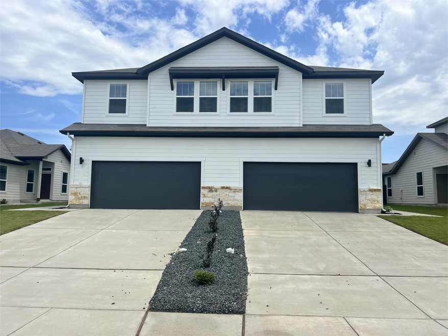 View of front facade with stone siding, a garage,