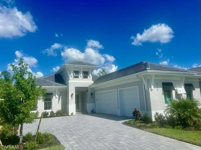 Ranch-style house featuring stucco siding, a garage, decorative driveway, and a tile roof