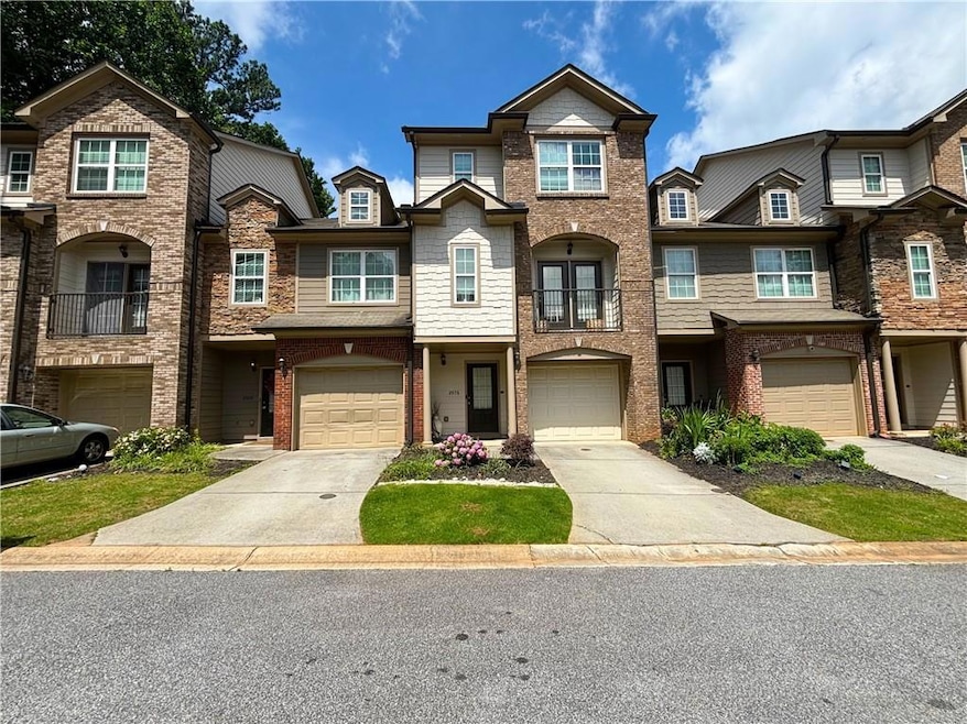 Multi unit property featuring an attached garage, driveway, brick siding, and a balcony