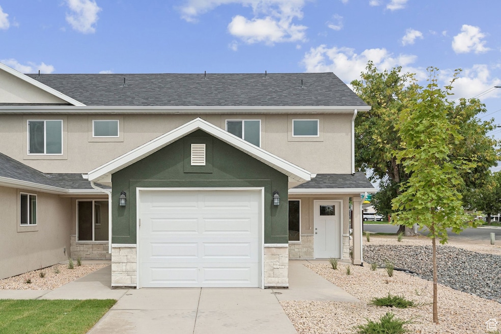 Traditional-style home with stone siding, stucco siding, a shingled roof, and a garage