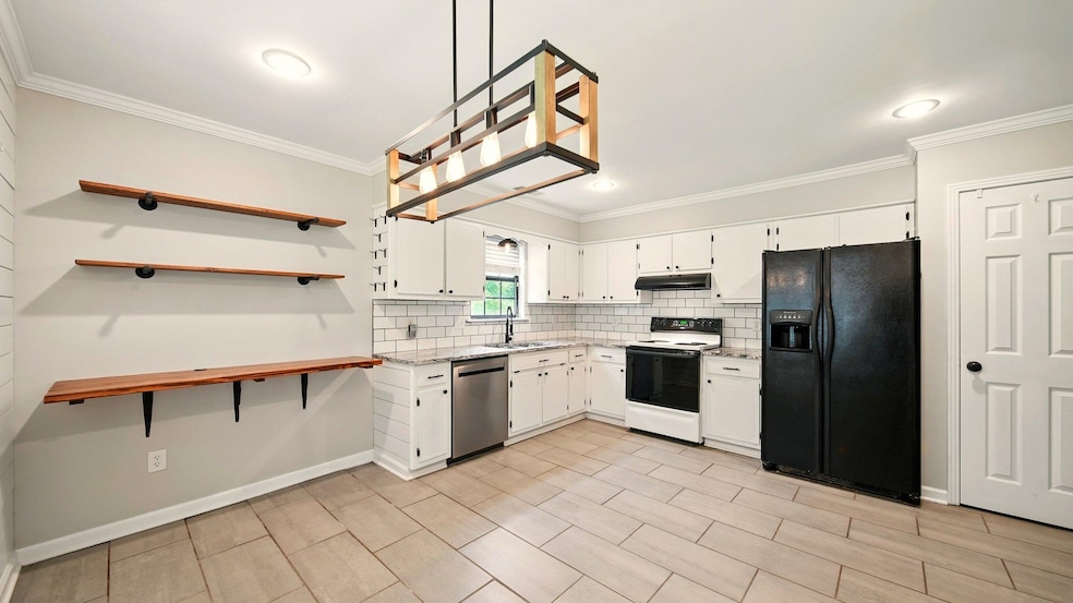 Kitchen featuring black refrigerator, electric range, stainless steel dishwasher, a sink, and under cabinet range hood